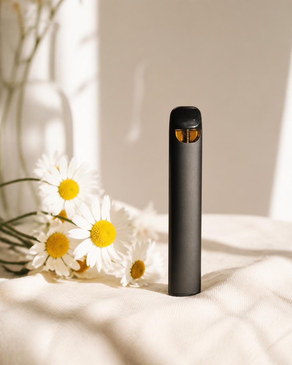 Dayzees solventless live rosin disposable vape standing beside white daisies